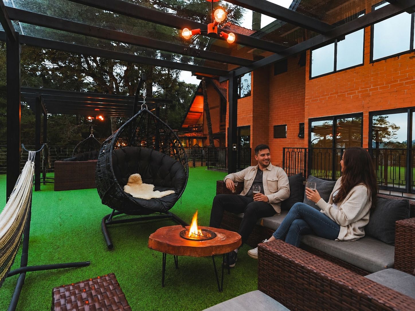 Casal no lounge do hotel com o fogo de chão aceso ao entardecer
